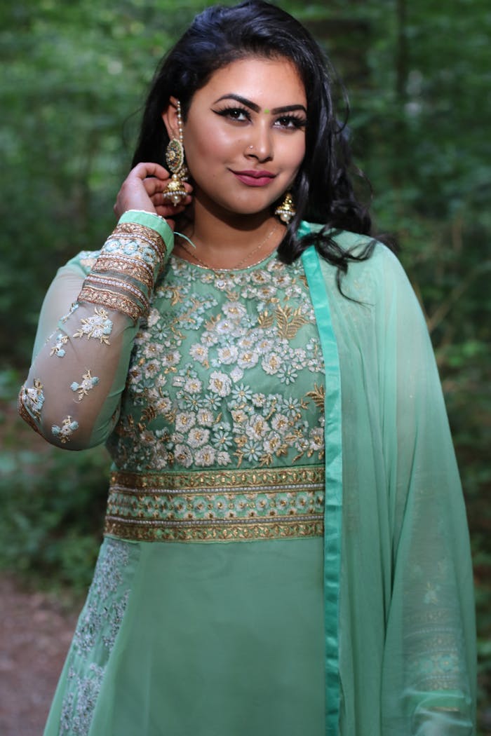 Beautiful woman in traditional attire posing elegantly in a lush forest setting.